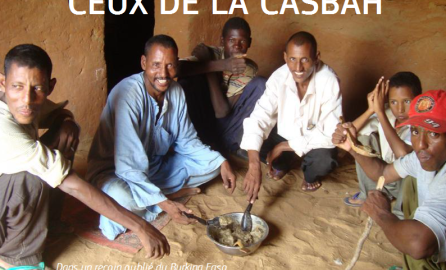 Men sitting on the floor, sharing food and smiling