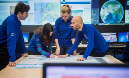 Photo of four people in an office with EU t-shirts around a table discussing plans