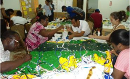 Photo of six people around a table with a colorful tablecloth doing an activity