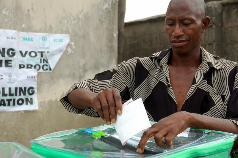 a man inserting a ballot paper into the ballot box