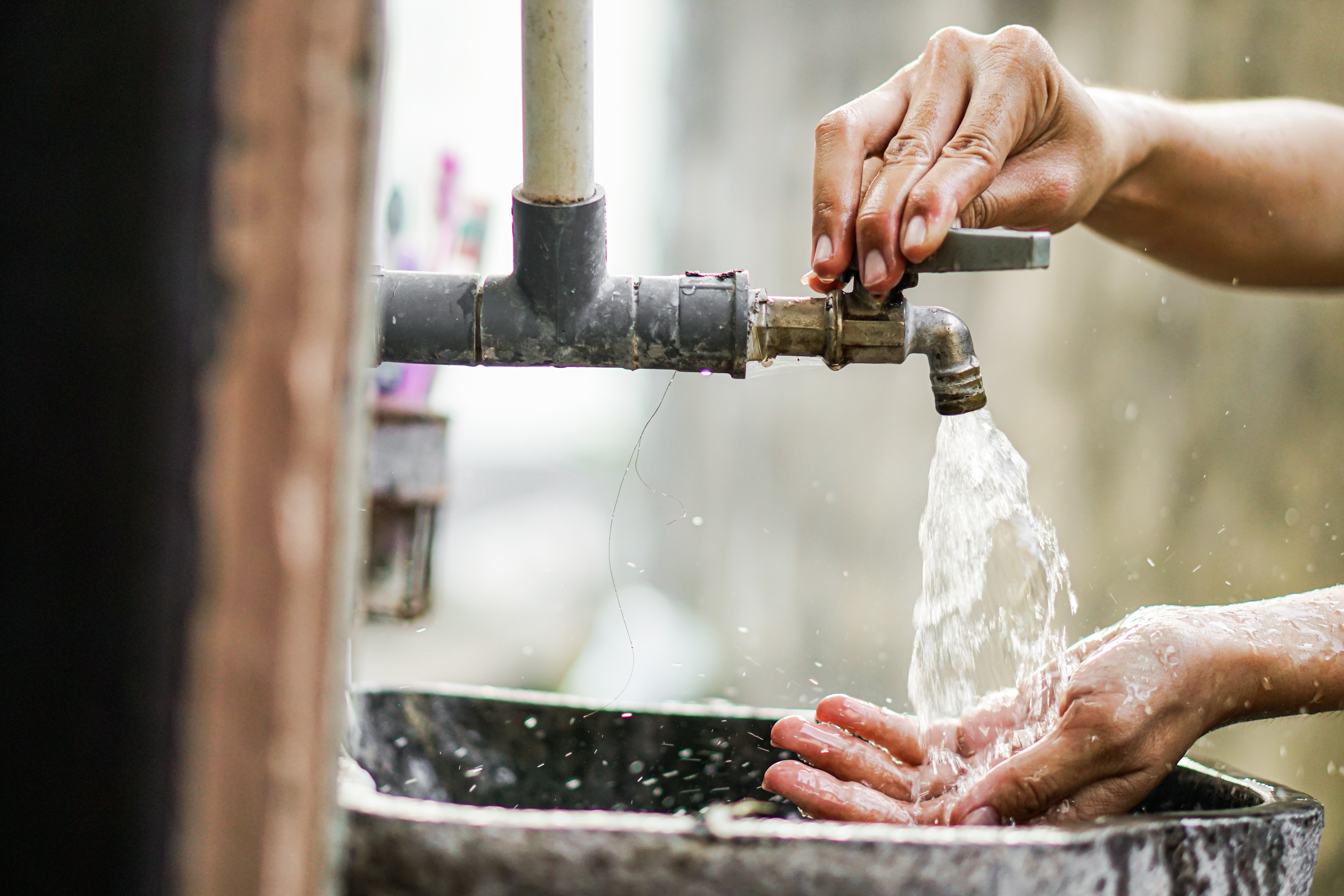 Water tap with hands opening the tap