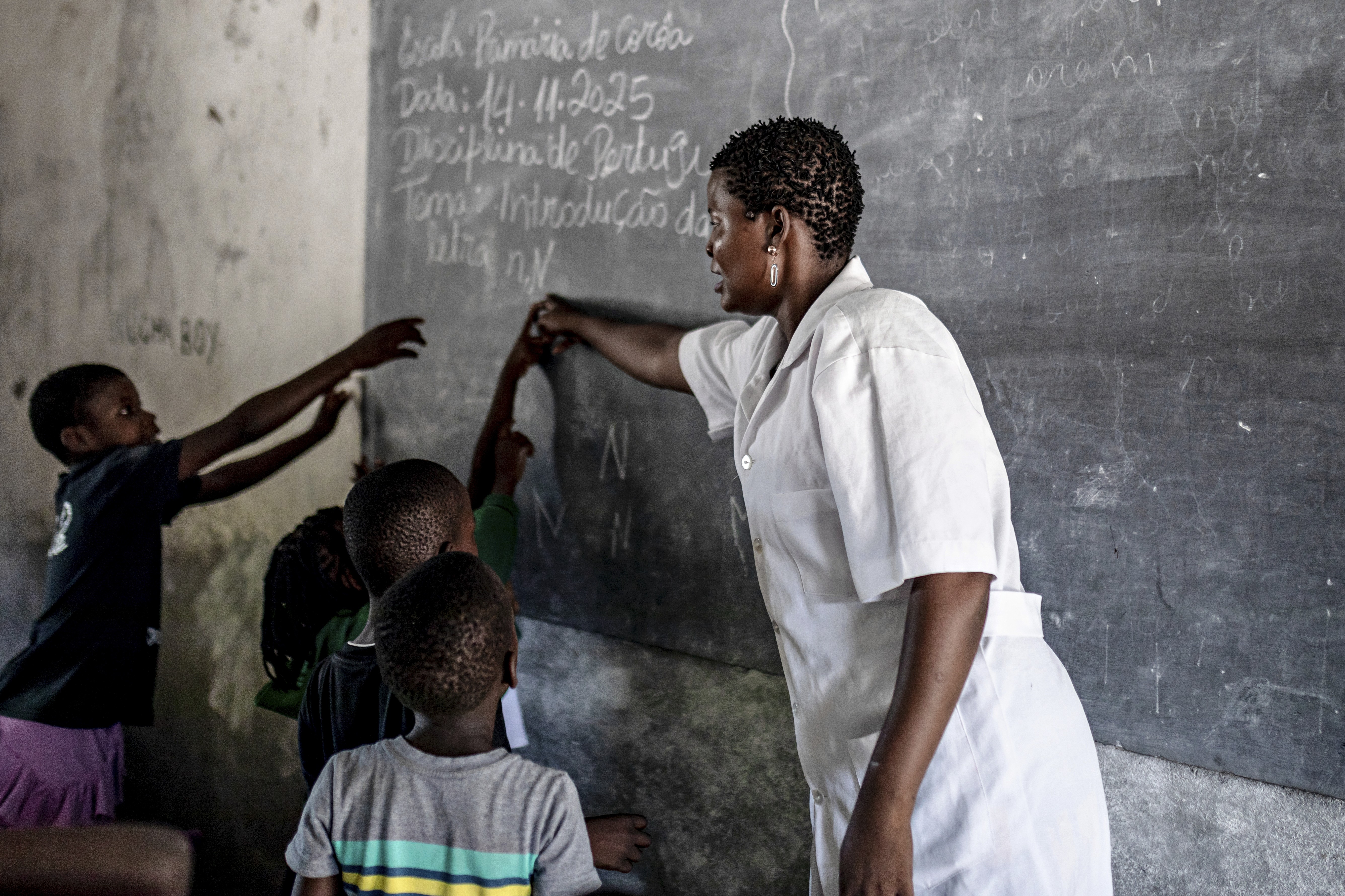 Teacher and students are in the classroom, working on the board together.