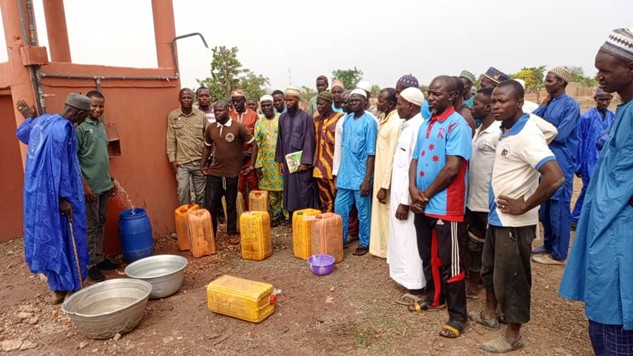 People standing around a water point with containers