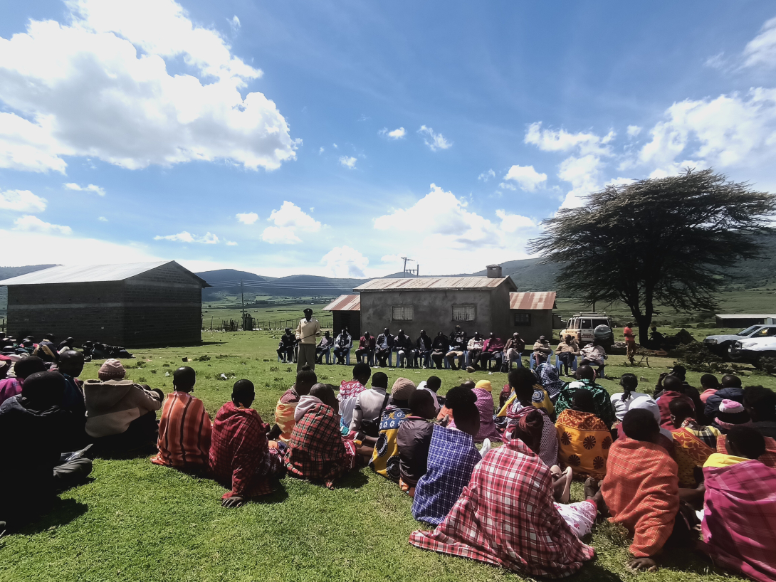 people sitting on grass at a community meeting