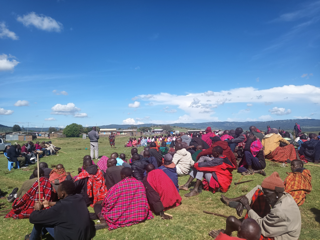 Group of people sitting on grass at community meeting
